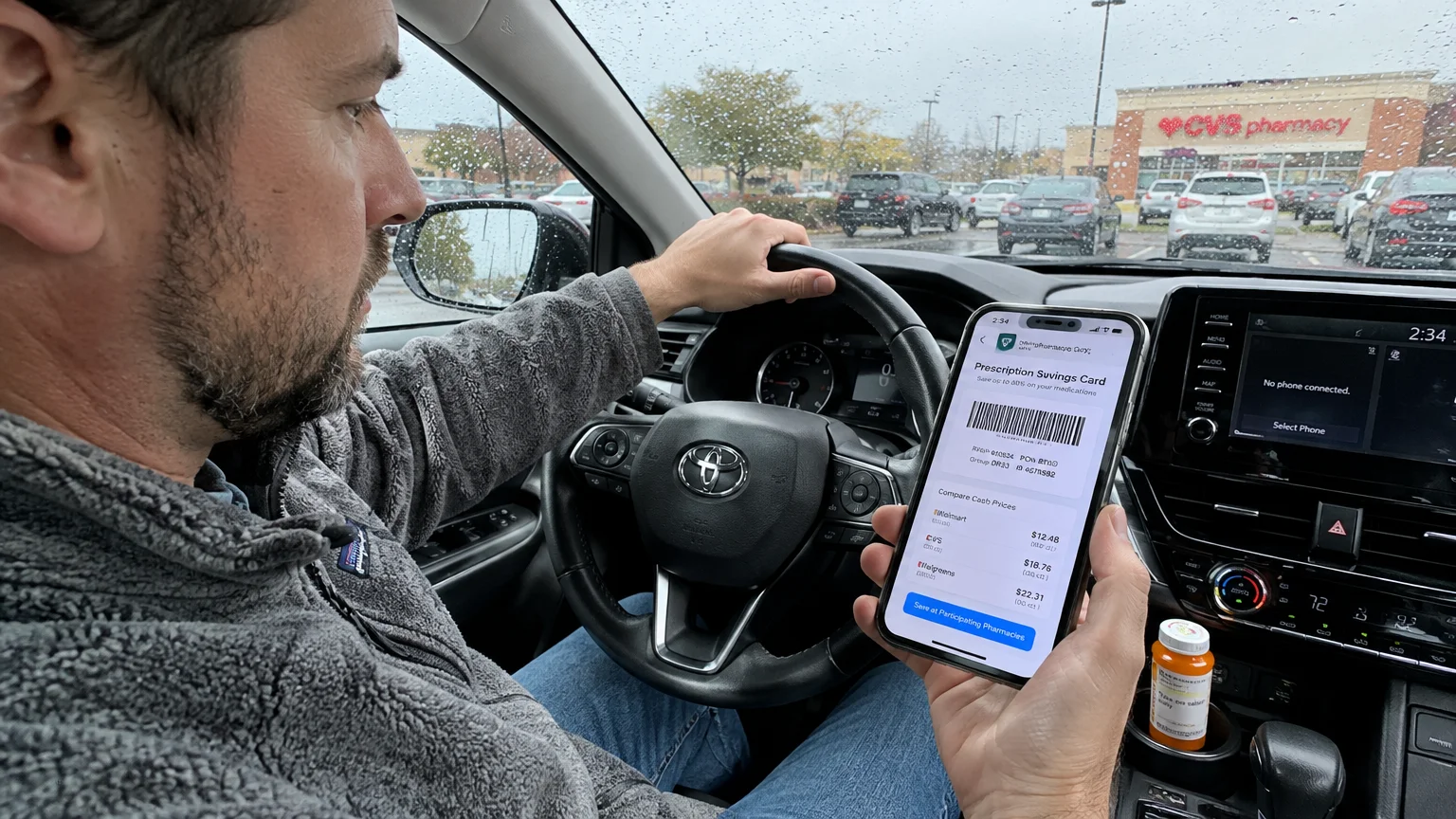 A man in a car holds a smartphone displaying a prescription savings card app with pharmacy price comparisons.